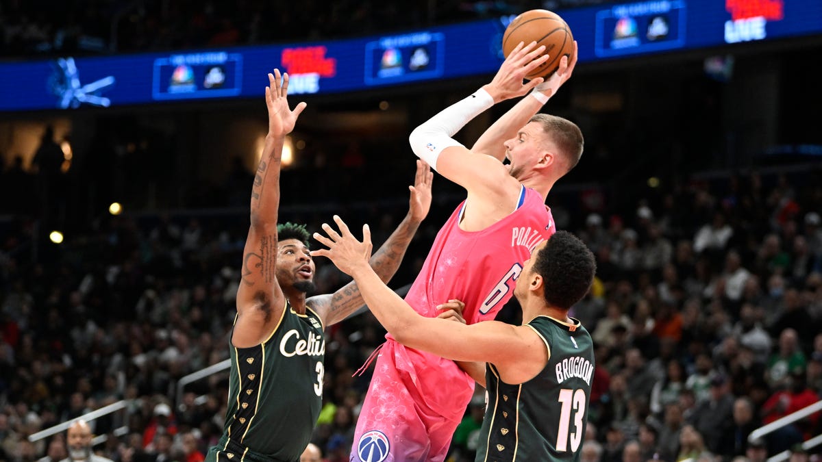 Washington Wizards center Kristaps Porzingis (6) looks to pass between Boston Celtics guard Malcolm Brogdon (13) and guard Marcus Smart (36) during the second half at Capital One Arena. Mandatory Credit: Brad Mills-USA TODAY Sports