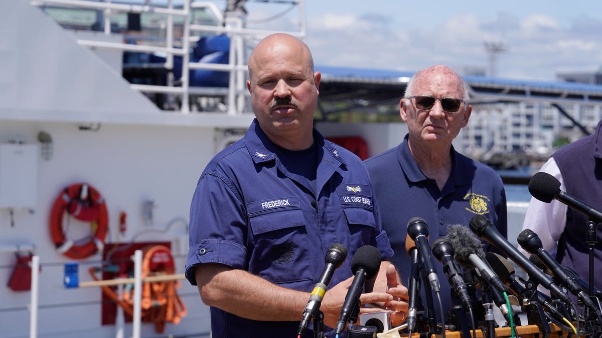 U.S. Coast Guard Capt. Jamie Frederick, left, faces reporters as Paul Hankins, U.S. Navy civilian contractor, supervisor of salvage, right, looks on during a news conference, Wednesday, June 21, 2023, at Coast Guard Base Boston, in Boston.