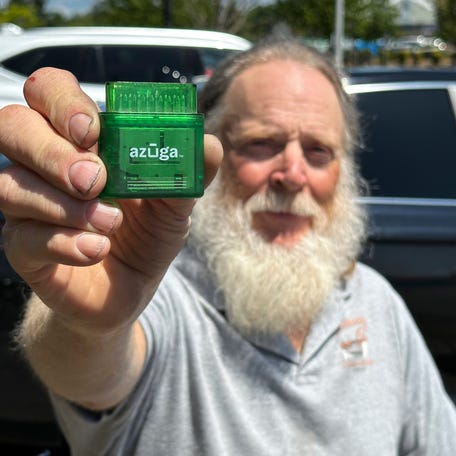 Evan Burroughs, who touts the virtues of an Oregon pilot program that charges motorists by the distance their vehicle travels rather than the gas it uses, displays a tracking device the program uses, in Salem, Ore., on Wednesday June 21, 2023. U.S. states are experimenting with road usage charging programs aimed at one day replacing motor fuel taxes, which are generating less each year, in part due to fuel efficiency and the rise of electric cars. (AP   Photo/Andrew Selsky)