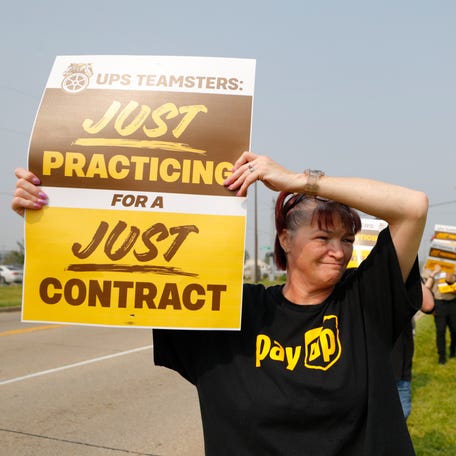 UPS worker Geraldine Dawson holds up a sign while wearing a t-shirt with the logo 'Pay Up' in the style of United Parce Service as she and members of Teamsters Local 89 began a practice strike outside Worldport, the largest sorting and logistics facility in America Wednesday morning in Louisville, Ky. June 28, 2023