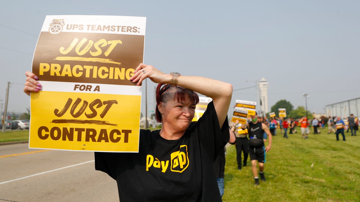 UPS worker Geraldine Dawson holds up a sign while wearing a t-shirt with the logo 'Pay Up' in the style of United Parce Service as she and members of Teamsters Local 89 began a practice strike outside Worldport, the largest sorting and logistics facility in America Wednesday morning in Louisville, Ky. June 28, 2023