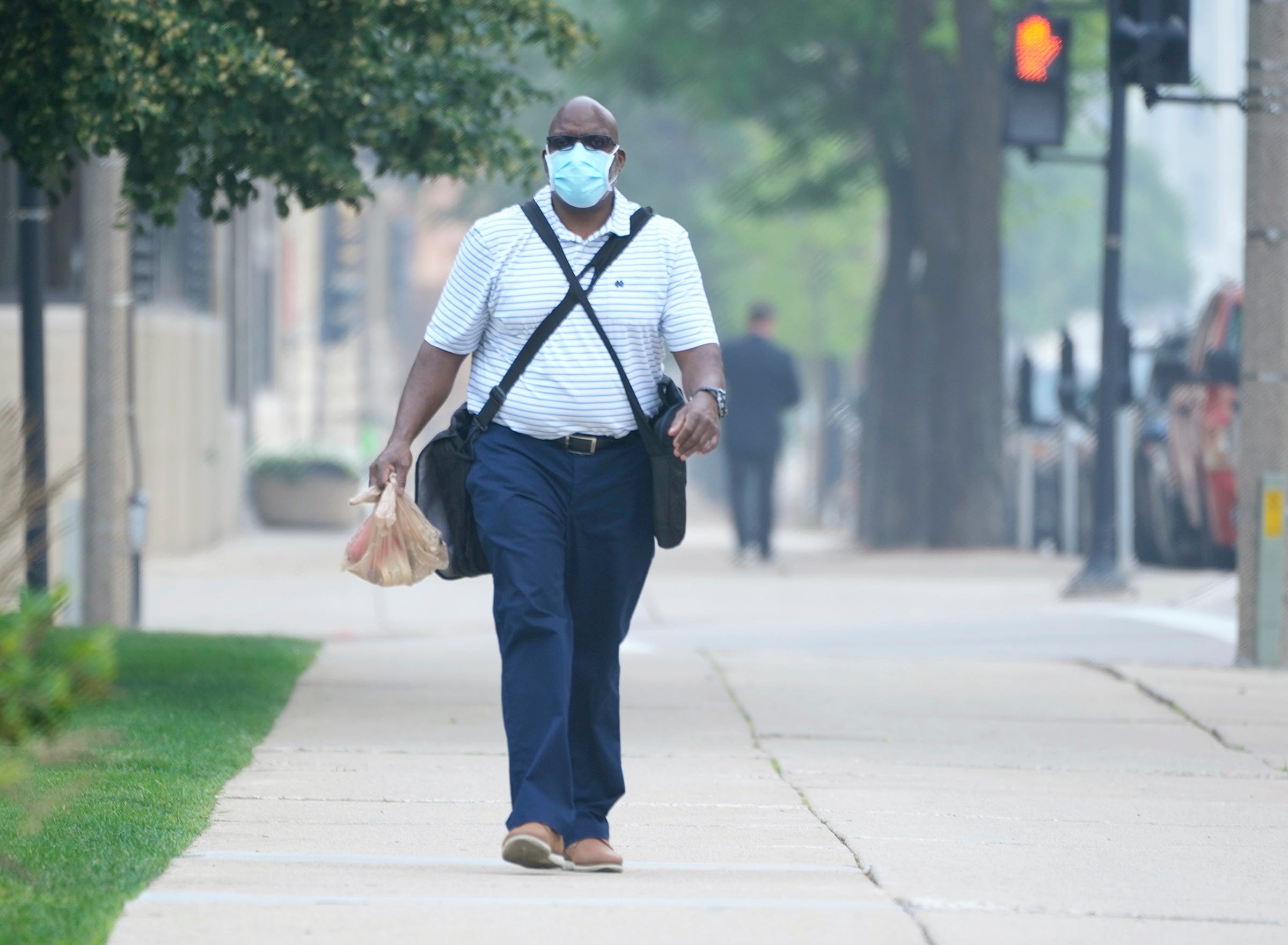 Tony Smith, who works for the City of Milwaukee, uses a mask to protect himself from the Canada wildfire smoke as he heads to work at the Frank P. Zeidler Municipal Building on North Broadway in Milwaukee on Wednesday, June 28, 2023. The quality of Wisconsin's unhealthy air continues from Canadian wildfires.