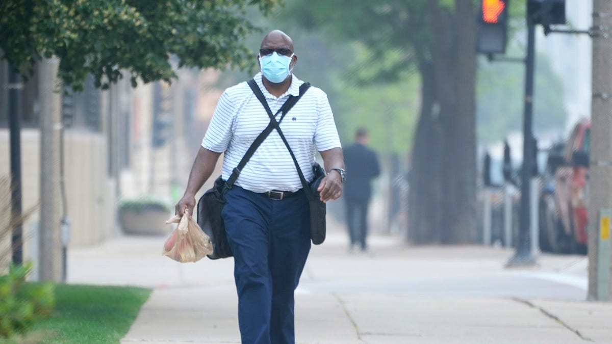 Tony Smith, who works for the City of Milwaukee, uses a mask to protect himself from the Canada wildfire smoke as he heads to work at the Frank P. Zeidler Municipal Building on North Broadway in Milwaukee on Wednesday, June 28, 2023. The quality of Wisconsin's unhealthy air continues from Canadian wildfires.