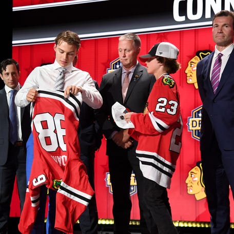 Connor Bedard puts on a Chicago Blackhawks jersey after being taken with the first pick in the 2023 NHL draft.