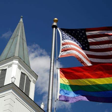 FILE - A gay Pride rainbow flag flies with the U.S. flag in front of the Asbury United Methodist Church in Prairie Village, Kan., on Friday, April 19, 2019. As of June 2023, more than 6,000 United Methodist congregations — a fifth of the U.S. total — have now received permission to leave the denomination amid a schism over theology and the role of LGBTQ people in the nation's second-largest Protestant denomination. (AP Photo/Charlie Riedel, File) ORG   XMIT: NY487