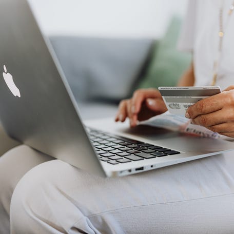 Person Using a Macbook and Holding a Credit Card