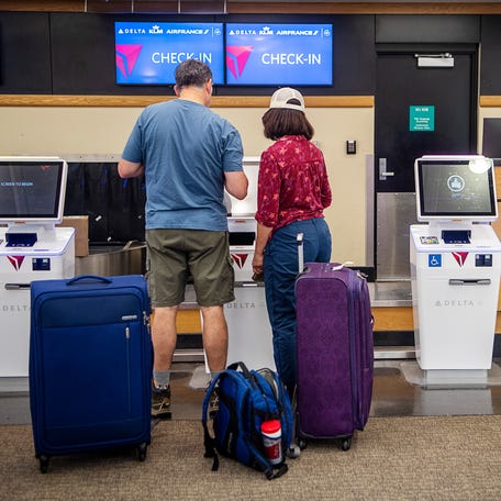 Travelers check in for their flight at a Delta Airlines kiosk in the Asheville Airport July 14, 2023.
