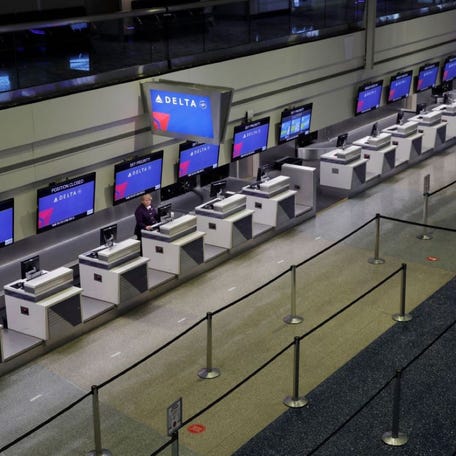 In this April 21, 2020, file photo, a lone person works at the Delta airlines check-in desk at Harry Reid International Airport in Las Vegas.