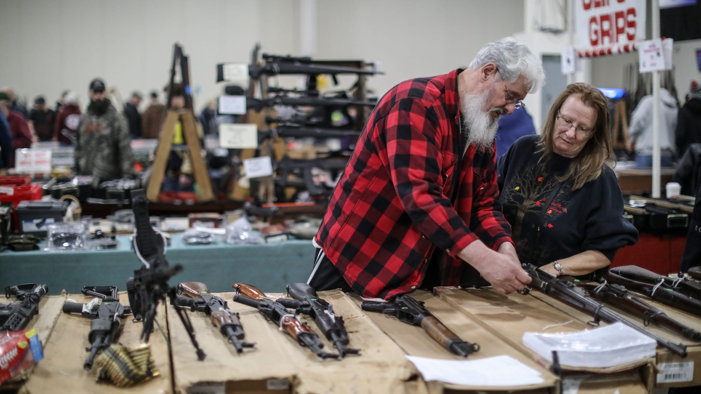 Mike Sadley, 64, and his wife, Jennie Sadley, 59, both of Wayne look over different guns, during the Novi Gun and Knife Show at Suburban Collection Showplace in Novi, Mich. on Feb. 24, 2018.