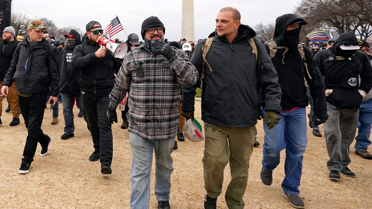 In this Jan. 6, 2021, file photo, Proud Boys including Joseph Biggs, front left, walks toward the U.S. Capitol in Washington, in support of President Donald Trump. With the megaphone is Ethan Nordean, second from left.