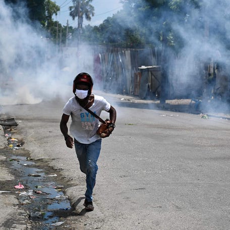 A man runs for cover from tear gas fired by police during a protest against insecurity in Port-au-Prince, Haiti, on August 14, 2023.