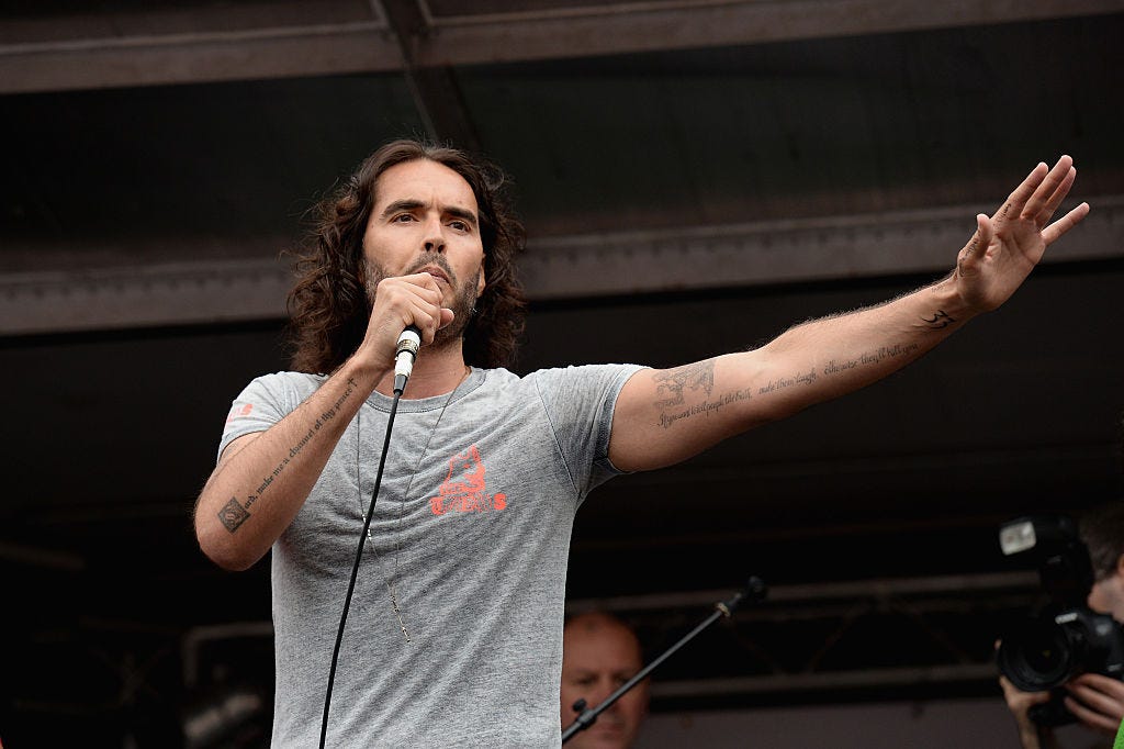 LONDON, ENGLAND - JUNE 20:  Comedian Russell Brand speaks to thousands of demonstrators gathered in Parliament Square to protest against austerity and spending cuts on June 20, 2015 in London, England. Thousands of people gathered to march from the City of London to Westminster, where they listened to addresses from singer Charlotte Church and comedian Russell Brand as well as Len McCluskey, general secretary of Unite and Sinn Fein's Martin McGuinness.    (Photo by Mary Turner/Getty Images)
