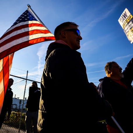 UAW members Dan Schlieman, with flag, and Brad Geer work the picket line during a strike Tuesday, Sept. 19, 2023, at the Stellantis Toledo Assembly Complex where Jeeps are made in Toledo, Ohio. (Jeremy Wadsworth/The Blade via AP) ORG XMIT: OHTOL207