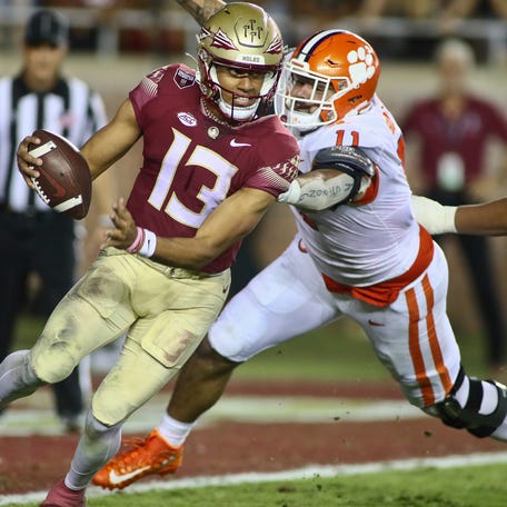 Florida State quarterback Jordan Travis (13) narrowly escapes the grasp of a Clemson defender during the team's game in 2022 at Doak Campbell Stadium