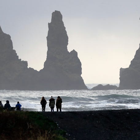 In this Oct. 26, 2016 file photo, people walk on the black sanded beach in Vik, Iceland, near the Volcano Katla.