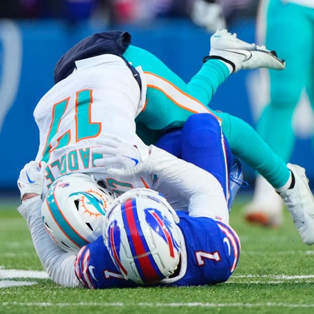 Miami Dolphins wide receiver Jaylen Waddle (17) is tackled by Buffalo Bills cornerback Taron Johnson (7) during the second half in a NFL wild card game at Highmark Stadium.